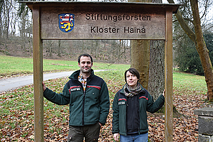 Dr. Fabian Schwaiger und Martha Töppe unter einem Schild mit der Aufschrift "Sitftungsforsten Haina"