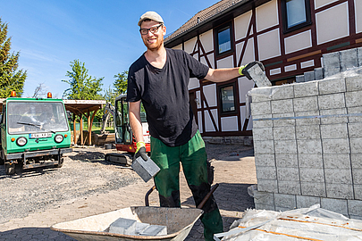 Steine von einer Palette auf eine Schubkarre verladen – "Das gehört alles dazu." Elmanuel Breitzke beim Verladen von Steinen auf eine Schubkarre